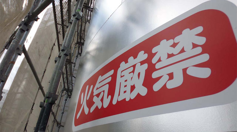 食用油精製工場のタンクへ水平に貼付した注意喚起シート、近接視点からの詳細