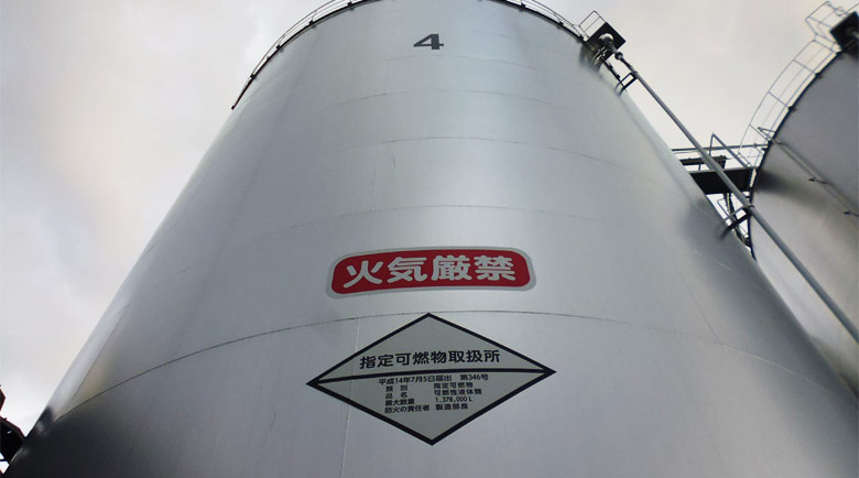 食用油精製工場のタンクへ水平に貼付した注意喚起シート、遠景全体像