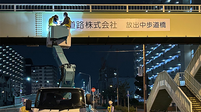 高所作業車に乗り夜間施工を行う作業員、遠景