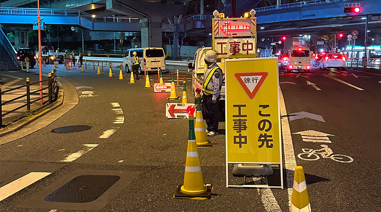 交通量が多い上に車線変更が複雑な交差点で誘導を行うガードマン