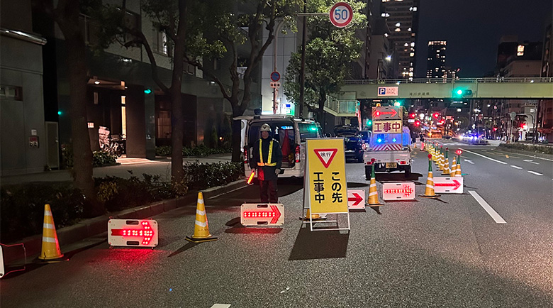 交通量の多い道路で夜間誘導作業を行う誘導員