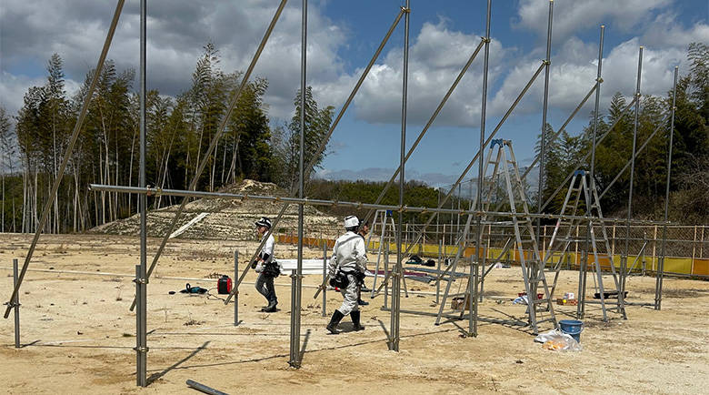 大型単管組野立て看板のパイプの微調整を行う作業員