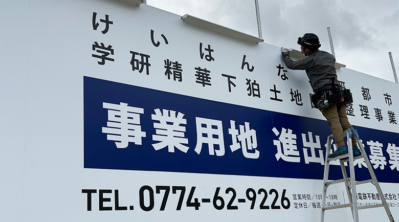 設置後の大型単管組野立て看板の最終チェックを行う作業員、左下からの様子